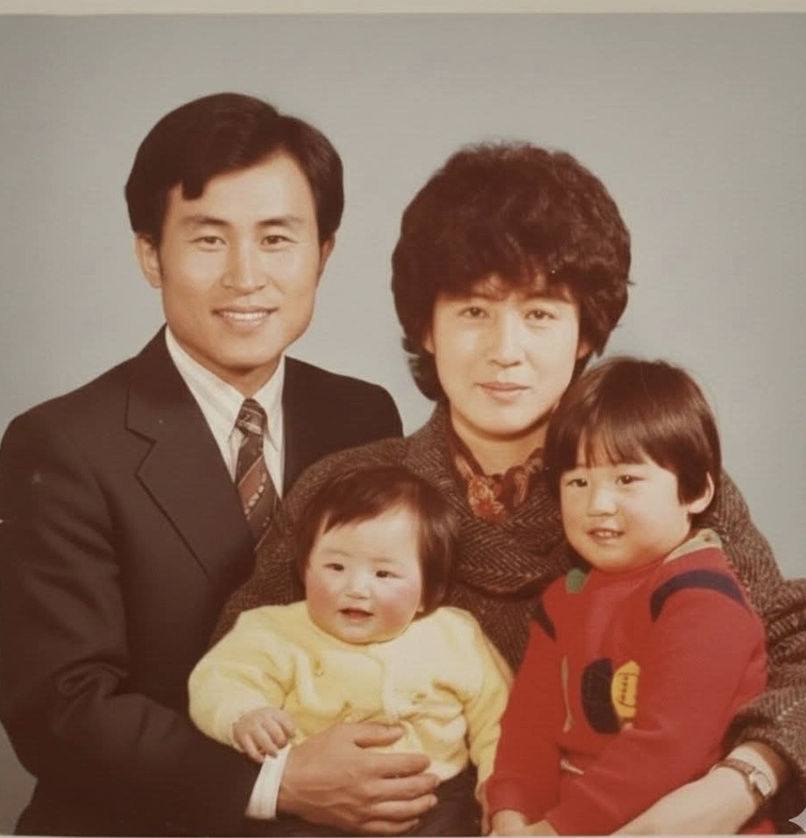 스튜디오 가족사진. 김영수 목사가 노란 옷의 막내를, 아내가 붉은 옷의 큰딸을 안고 함께 앉아 있다.