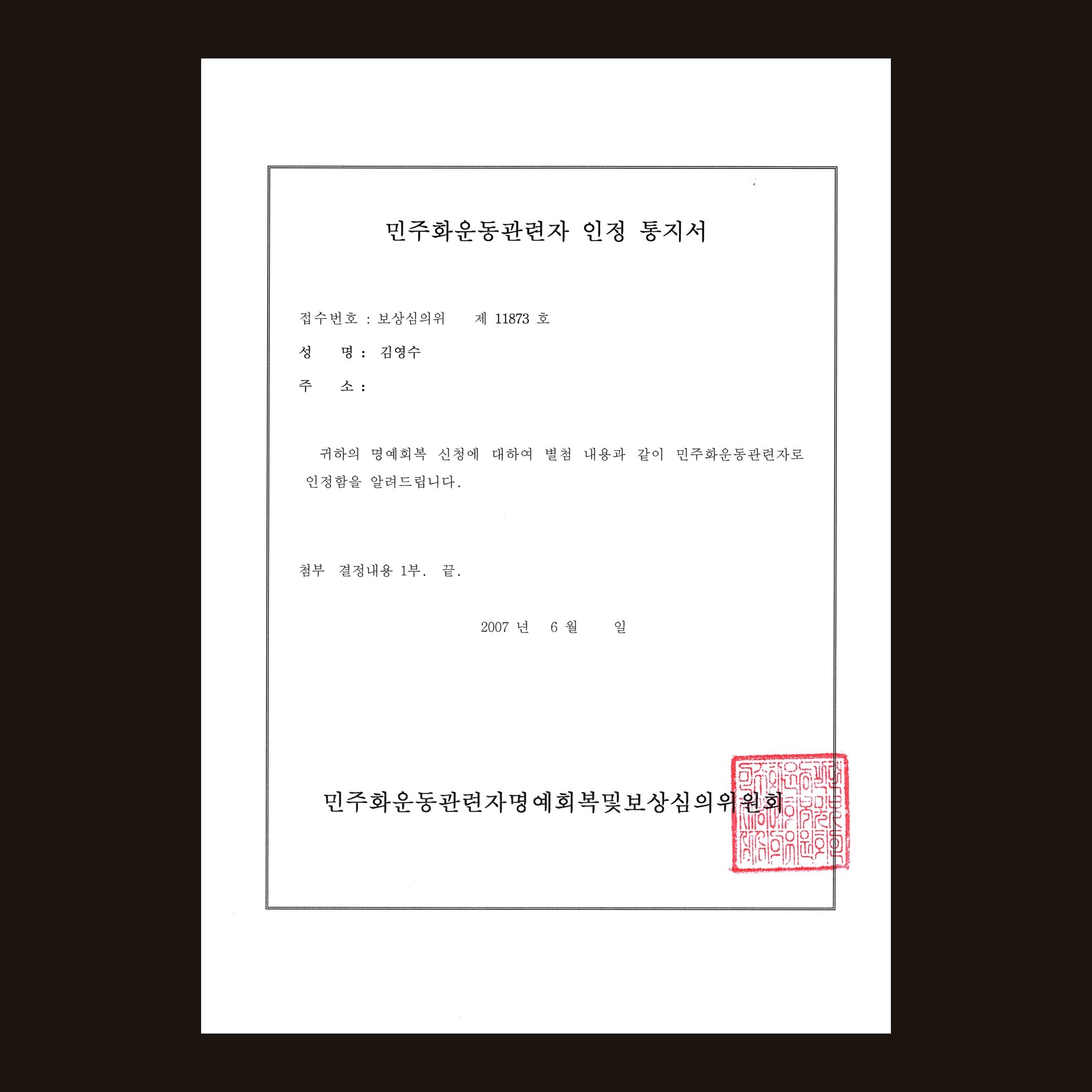 민주화운동관련자 인정 통지서. '귀하의 명예회복 신청에 대하여 민주화운동관련자로 인정함을 알려드립니다'라고 적혀 있고 위원회 직인이 찍혀 있다.